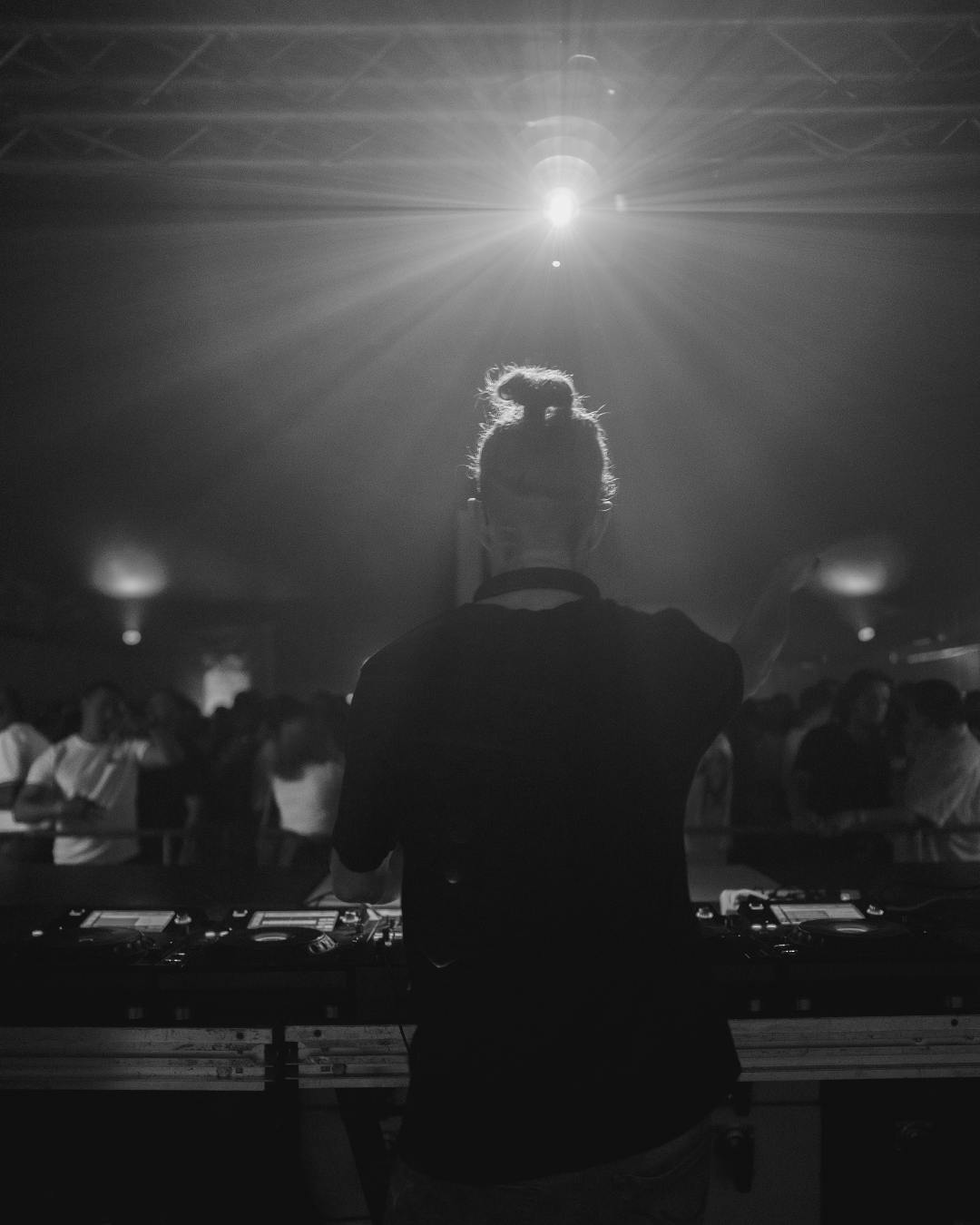 DJ hinter dem Pult im Gegenlicht